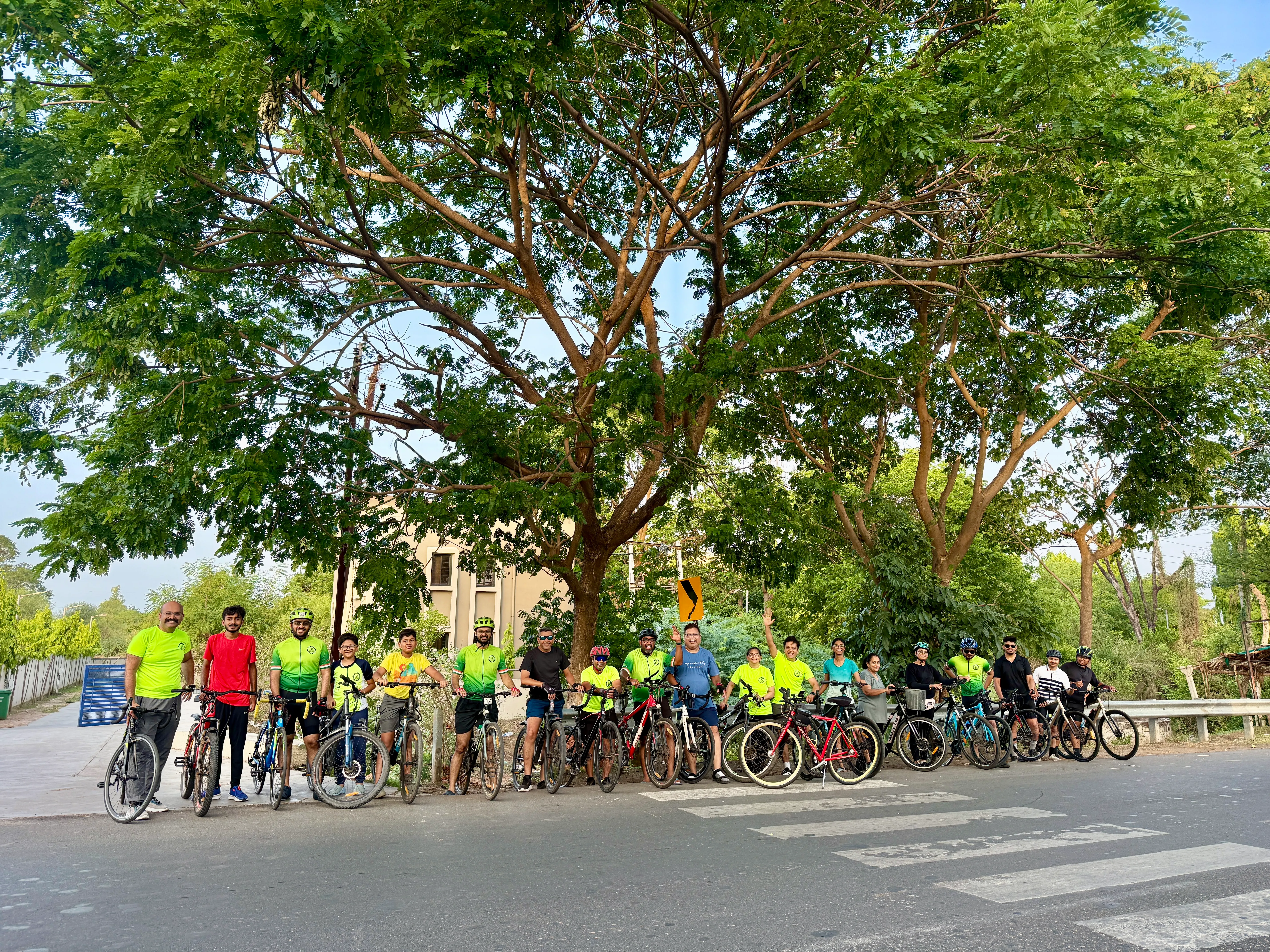 Anand Cycling Club riders lined up with bikes on scenic tree-lined highway